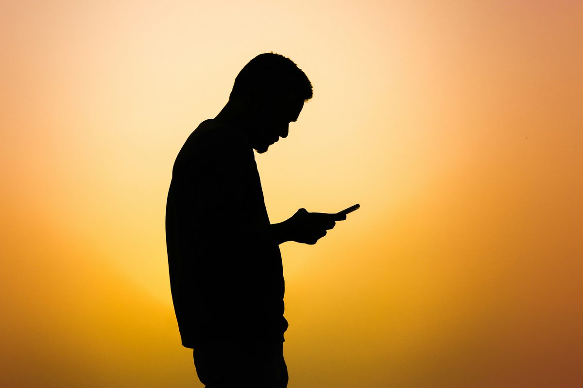 Silhouette d'un homme consultant son téléphone — illustration smishing